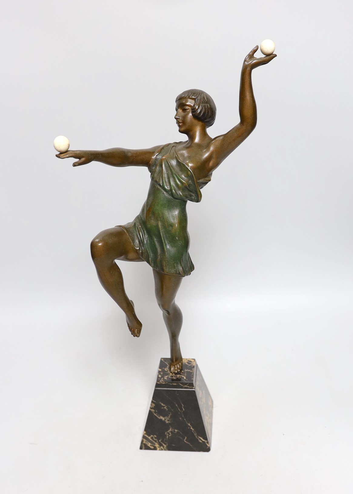 A French Art Deco patinated bronzed spelter dancer, holding two ivory spheres, on marble base, attributed to J. Limousin, 44cms high